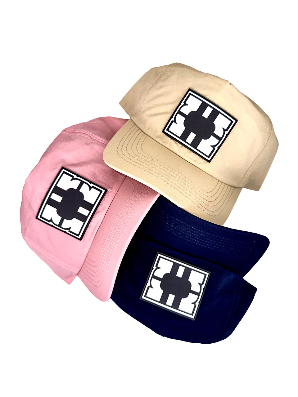 Three hats in pink, beige, and navy with a black and white logo on a white background